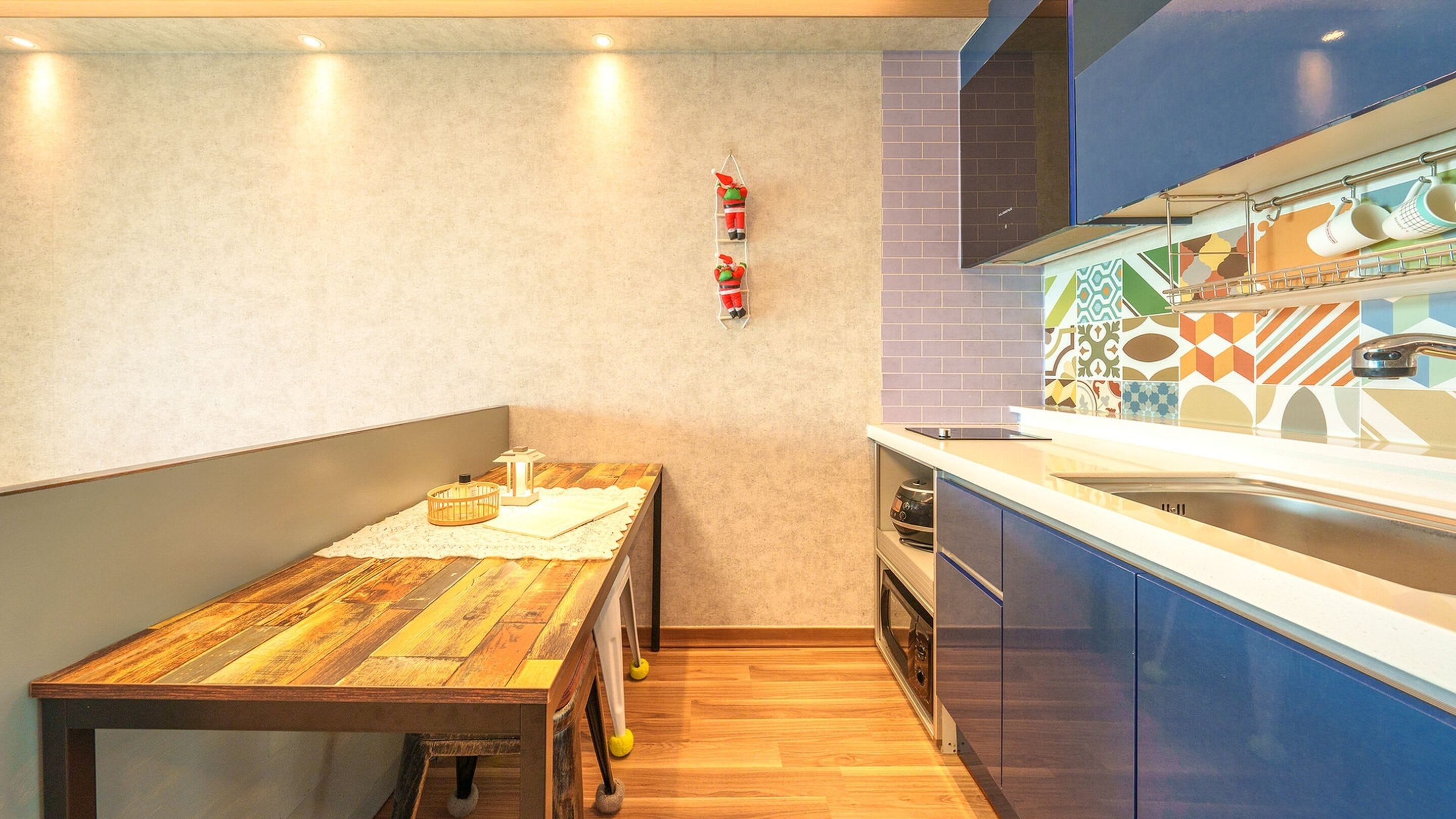 A compact kitchen with a wooden table, a built-in oven, and a colorful backsplash.