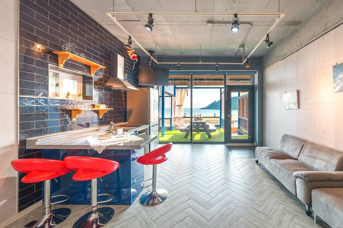 Une cuisine moderne avec un coin bar, un canapé et une vue sur la plage.