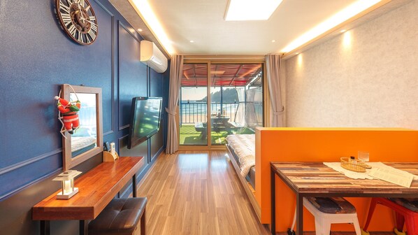 Een hotelkamer met een bed, een bureau, een televisie en een balkon met uitzicht op het strand.