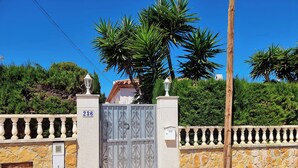 Un cancello chiuso da un muro in pietra e un viale con un numero.