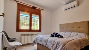 Una camera da letto con un letto, una sedia, un termosifone, una finestra vista e un condizionatore d'aria.