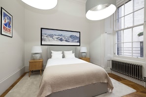 A bedroom with a bed, two bedside tables, a window, and a framed picture on the wall. - Modern studio in Edinburgh West End (Edinburgh)