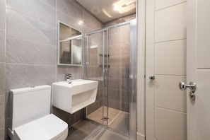 A modern bathroom with a toilet, sink, and glass-enclosed shower. - Modern studio in Edinburgh West End (Edinburgh)
