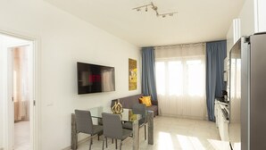 Een moderne woonkamer met een eethoek, een flatscreen televisie en een keuken.