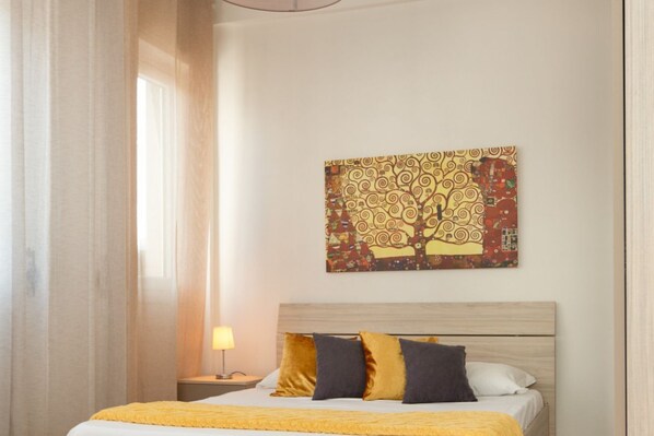Un dormitorio con una cama, una mesita de noche, una lámpara y un cuadro en la pared.