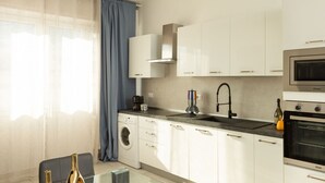 Een moderne keuken met witte kasten, een roestvrijstalen oven, een ingebouwde magnetron en een wasmachine.