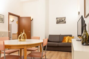 A modern living room with a round wooden dining table, two chairs, a sofa, and a coffee table. - Free Parking - Retreat in Milano Centrale (Milano)