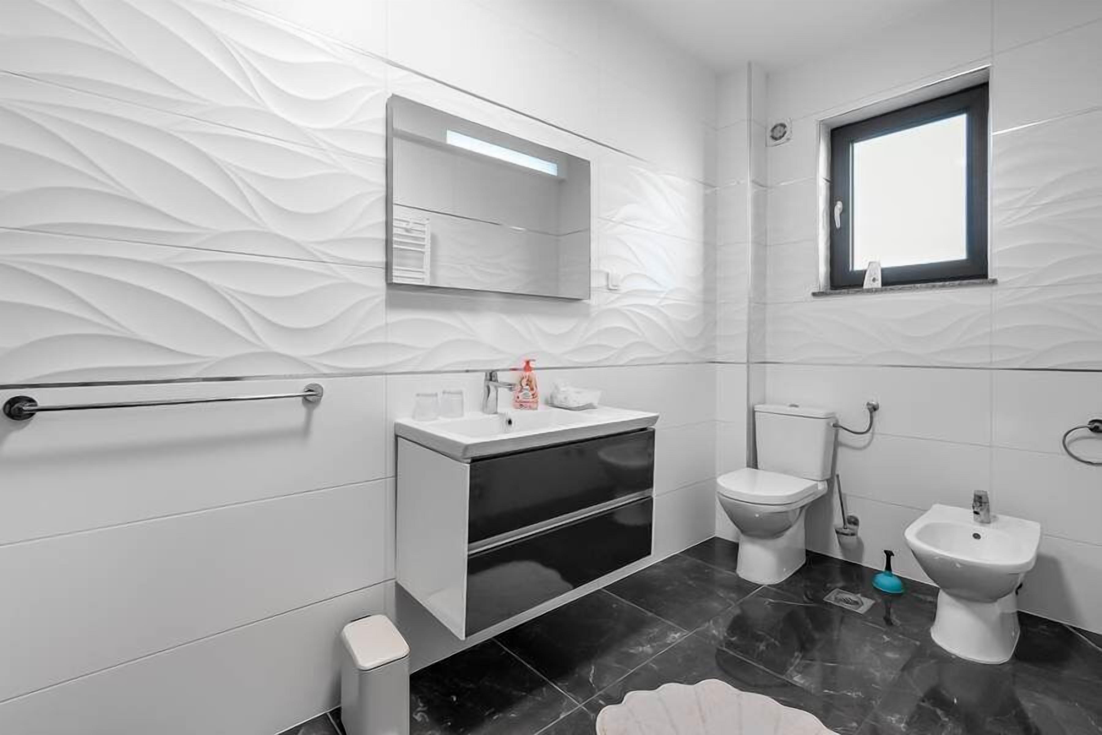 Un baño moderno con tocador, inodoro, bidé y ventana.