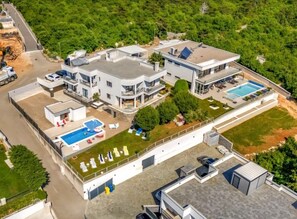 A modern residential complex with multiple buildings, a swimming pool, and a tennis court. - Villa Del Mar (Crikvenica)