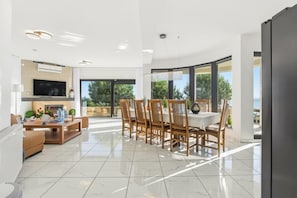 Un salon moderne avec un téléviseur, un canapé et un coin repas comprenant des chaises et une table.