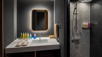 A modern bathroom with a white sink, a mirror, and a shower.