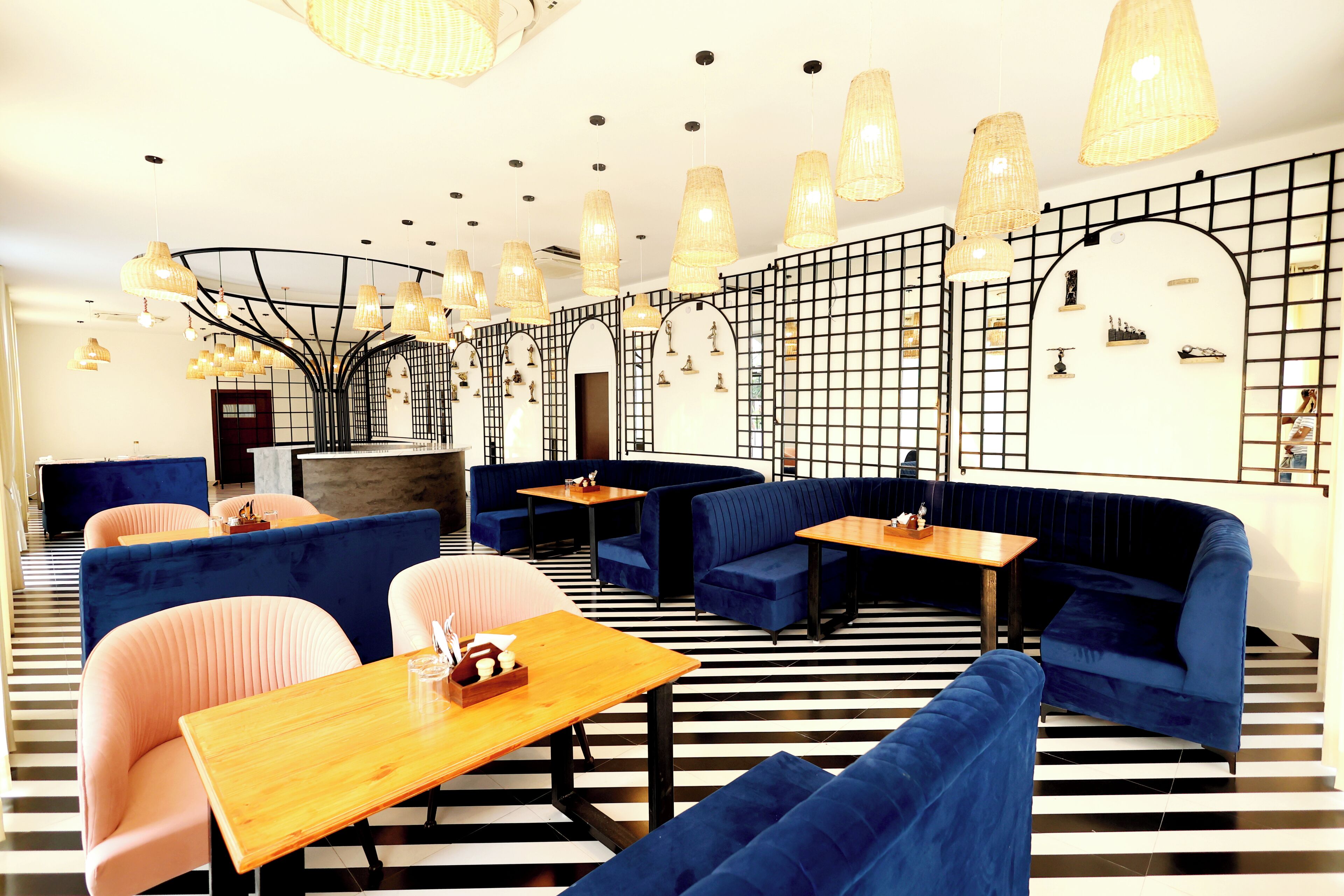 A modern interior with blue and pink seating, wooden tables, and unique lighting fixtures.