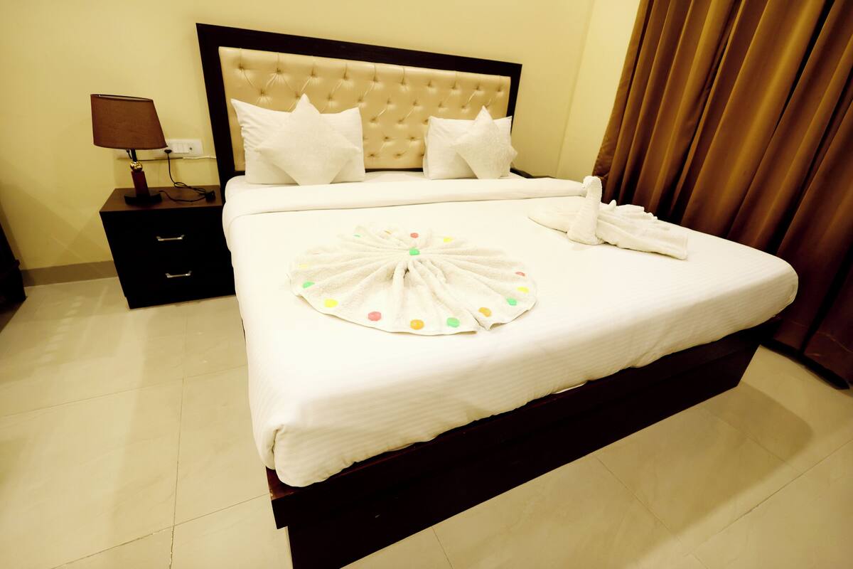 A neatly made bed with a white duvet, a decorative towel, and a bedside table with a lamp.