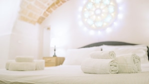 A cozy, well-lit room with a bed, neatly folded towels, and a unique arched ceiling. - Travel Old Bari (Bari)