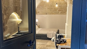 A room with a stone ceiling, a bed, a desk with a chair, and a window with a view of the stone ceiling. - Travel Old Bari (Bari)