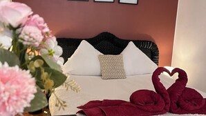 A hotel room with a bed, a vase of flowers, and a wall with framed pictures. - Jacuzzi balnéo center of bordeaux (Bordeaux)