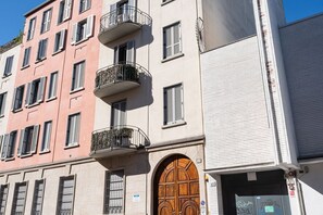 A multi-story building with balconies, a large wooden door, and a sign indicating a restaurant.