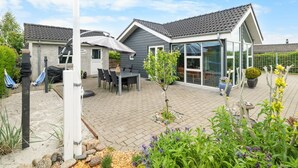 Una casa moderna con un patio, mobiliario exterior y un jardín.