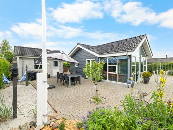 A modern house with a patio, outdoor seating, and a garden.