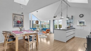 Amplia sala de estar con una mesa de comedor, sillas, sofá y una isla de cocina.