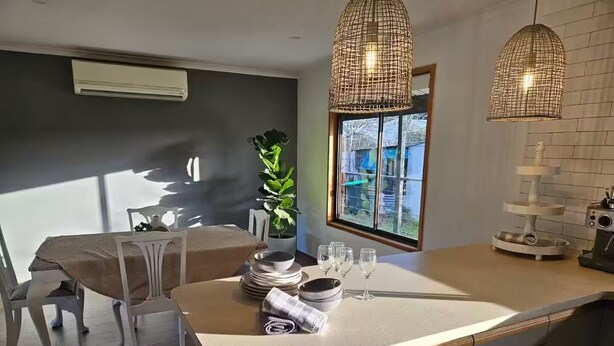A modern kitchen with a central island, white cabinetry, and a dining area with a table and chairs.