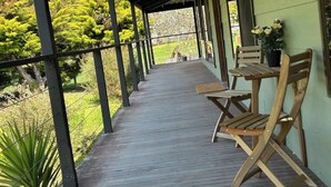 A covered outdoor area with a wooden deck, metal railings, and a table with chairs.