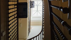 Eine Wendeltreppe mit einer Spiegelwand, die einen Raum mit einem Fenster und einer Tür widerspiegelt.