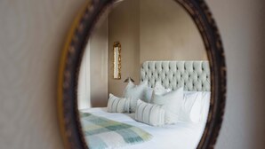 Ein Schlafzimmer mit einem gesteppten Kopfteil, einem Spiegel und einem Bett mit weißer Bettwäsche.