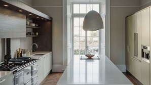 Eine moderne Küche mit einer zentralen Kochinsel, integrierten Geräten und einem großen Fenster für natürliches Licht.