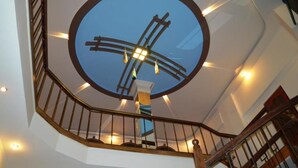 A spiral staircase with a circular skylight and modern lighting fixtures.