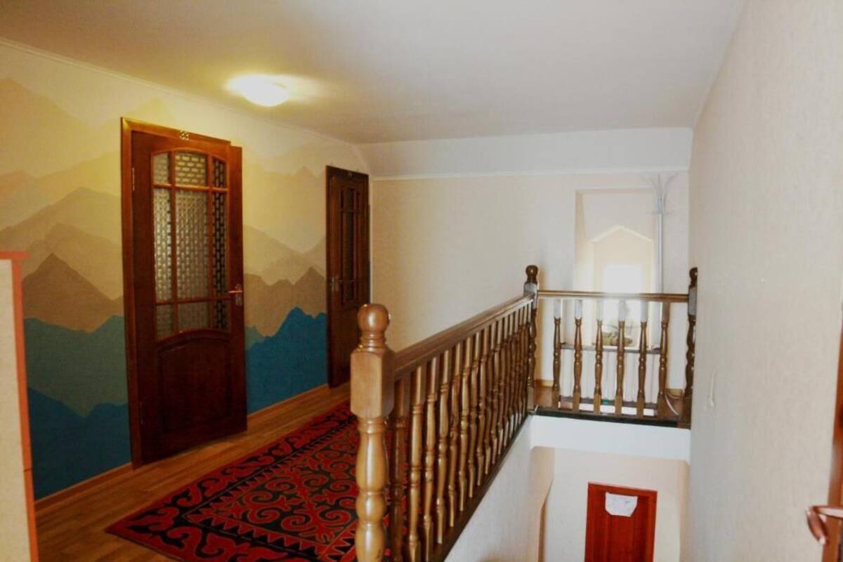 Eine Treppe mit einem hölzernen Geländer und einem roten Teppich mit Muster.