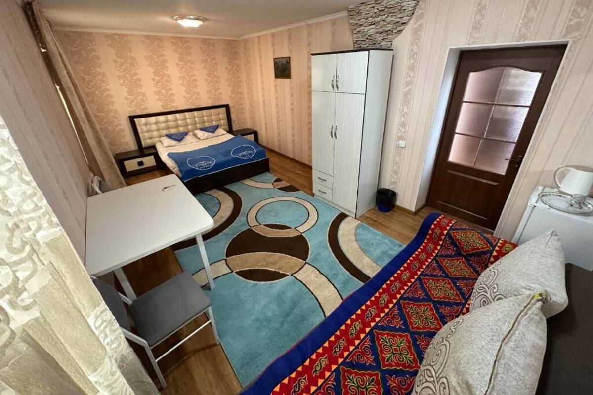 Ein gemütliches Hotelzimmer mit Bett, Schrank, kleinem Tisch und einem gemusterten Teppich.