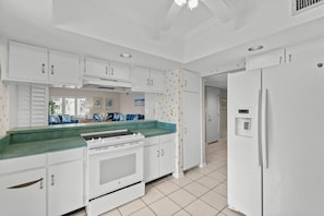 Una cocina con armarios blancos, una estufa y un refrigerador.