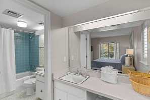 Un baño con bañera, inodoro, lavabo y un espejo grande.