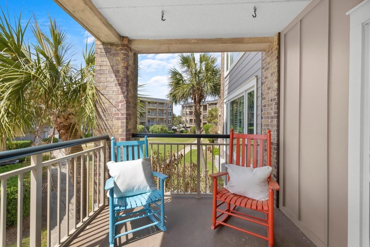 Un balcon avec deux fauteuils à bascule, un mur en briques et une vue sur les immeubles voisins.