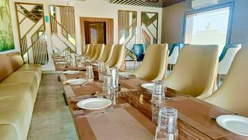 A long dining table with multiple chairs, each set with plates, cutlery, and glasses.