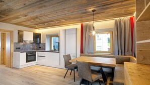 Een moderne keuken met witte kastjes, een ingebouwde oven en een raam met gordijnen.