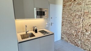 A compact kitchen with a built-in microwave, a sink, and a coffee machine.