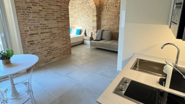 A kitchen with a sink and a dining area with a table and chairs.