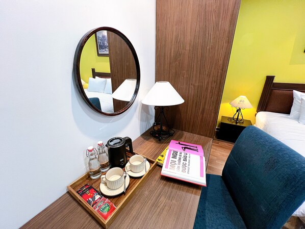 A hotel room with a bed, a bedside table with a lamp, a tray with cups, a book, and a mirror. - La Doma en Adagio - Sleep and Heal (Ho Chi Minh City)