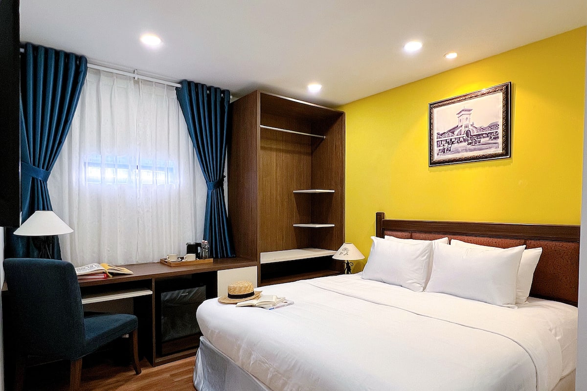 A hotel room with a bed, desk, chair, and a wardrobe.