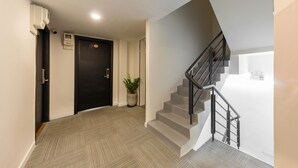 Ein modernes Interieur mit einer Treppe, einem Blumentopf und einer Tür mit Überwachungskamera.