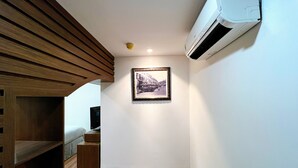 Ein Zimmer mit Holzboden, einem gerahmten Bild an der Wand und einer weißen Klimaanlage.