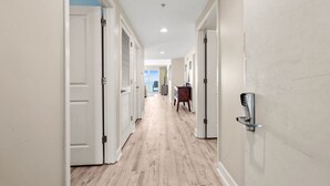 Un couloir avec des portes blanches, un plancher en bois et un clavier de sécurité fixé au mur de droite.