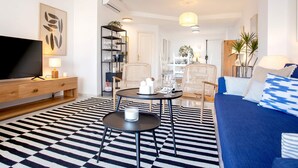 A modern living room with a large flat-screen TV, a coffee table, a sofa, and a dining area with chairs and a table. - Genteel Home Ricardo Soriano III (Marbella)