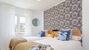 A double bed with a magazine, a round mirror, and patterned wallpaper. - Genteel Home Ricardo Soriano III (Marbella)