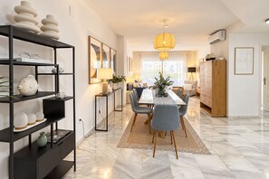 A modern living room with a dining area, featuring a marble floor, a bookshelf, and a large window with natural light. - Genteel Home Ricardo Soriano III (Marbella)
