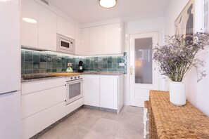 A modern kitchen with white cabinetry, a granite countertop, and a built-in oven. - Genteel Home Ricardo Soriano III (Marbella)