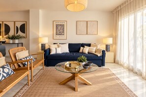 A modern living room with a blue sofa, two side tables with lamps, a glass coffee table, and a patterned rug. - Genteel Home Ricardo Soriano III (Marbella)