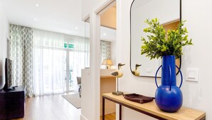 A modern hotel room with a wooden floor, a blue vase with green plants, a lamp, and a television on a black stand. - Genteel Home Ricardo Soriano II (Marbella)